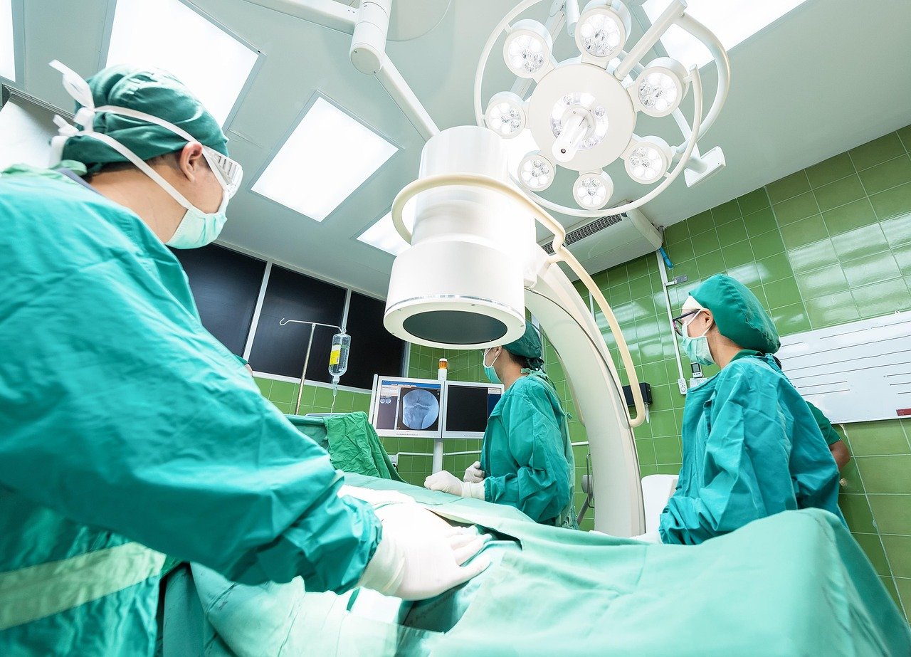 Zespół chirurgów na sali operacyjnej pod lampą operacyjną, aparatura medyczna wyceniana na potrzeby ubezpieczenia
