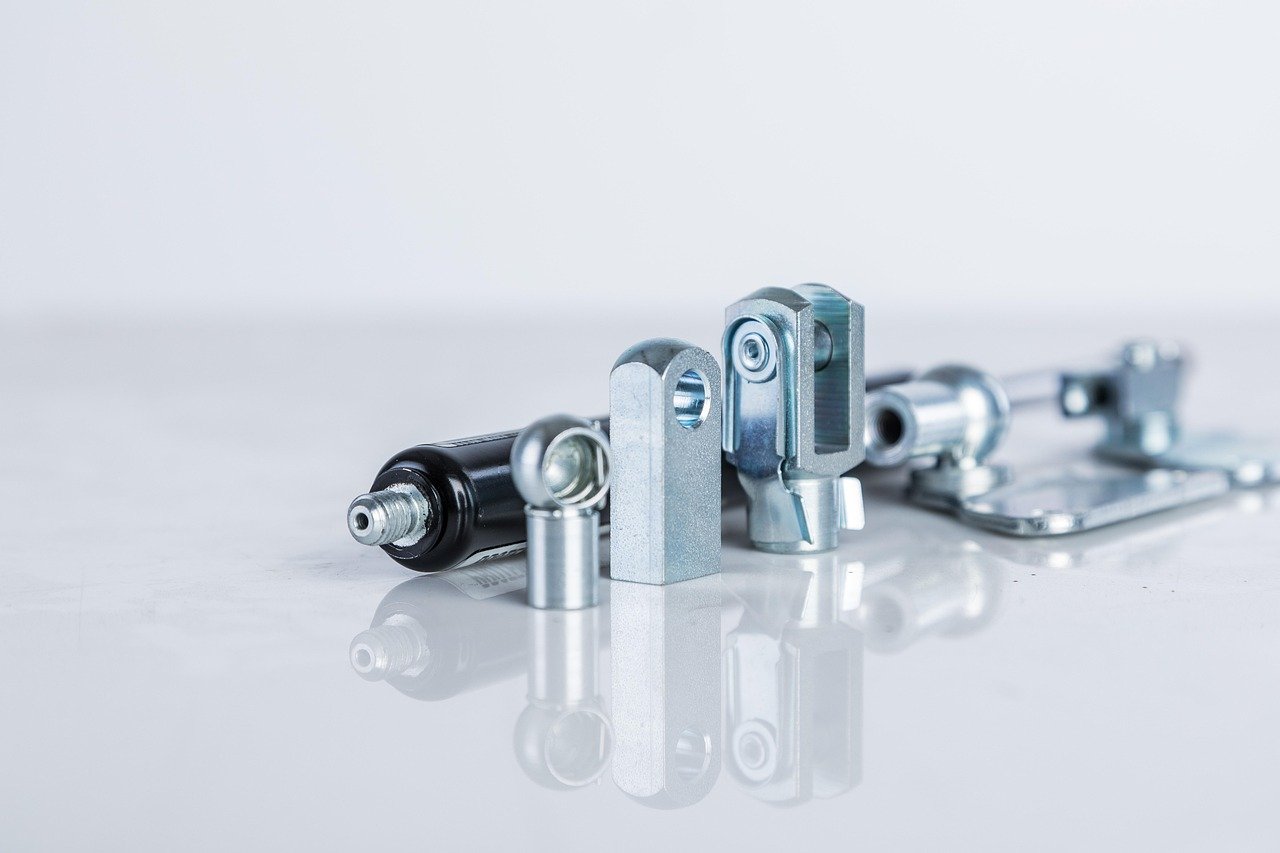 Metalowe łączniki i końcówki cięgien na jasnym tle, drobne podzespoły projektowane w 3D CAD